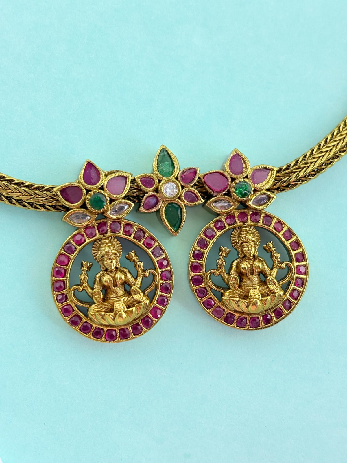 Premium antique finish necklace showcasing classic rich ruby and green stones with a lakshmi pendant and matching earrings