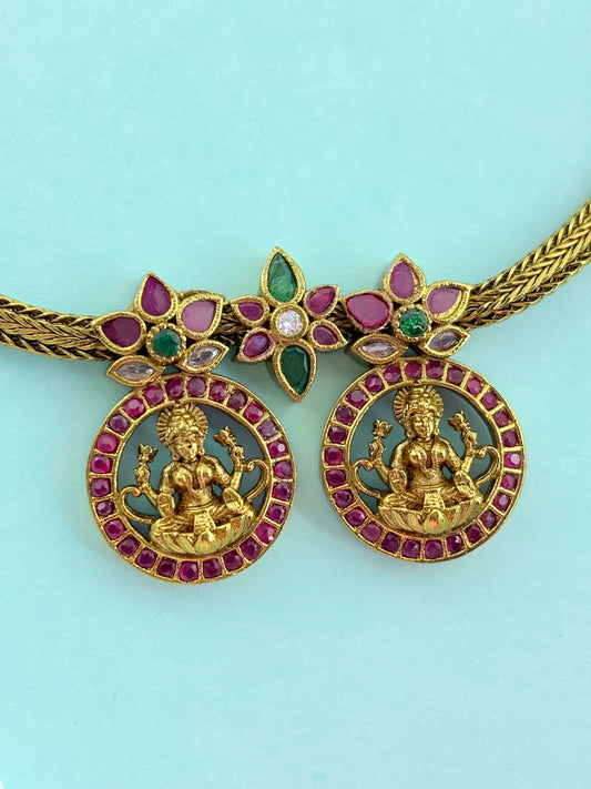Premium antique finish necklace showcasing classic rich ruby and green stones with a lakshmi pendant and matching earrings