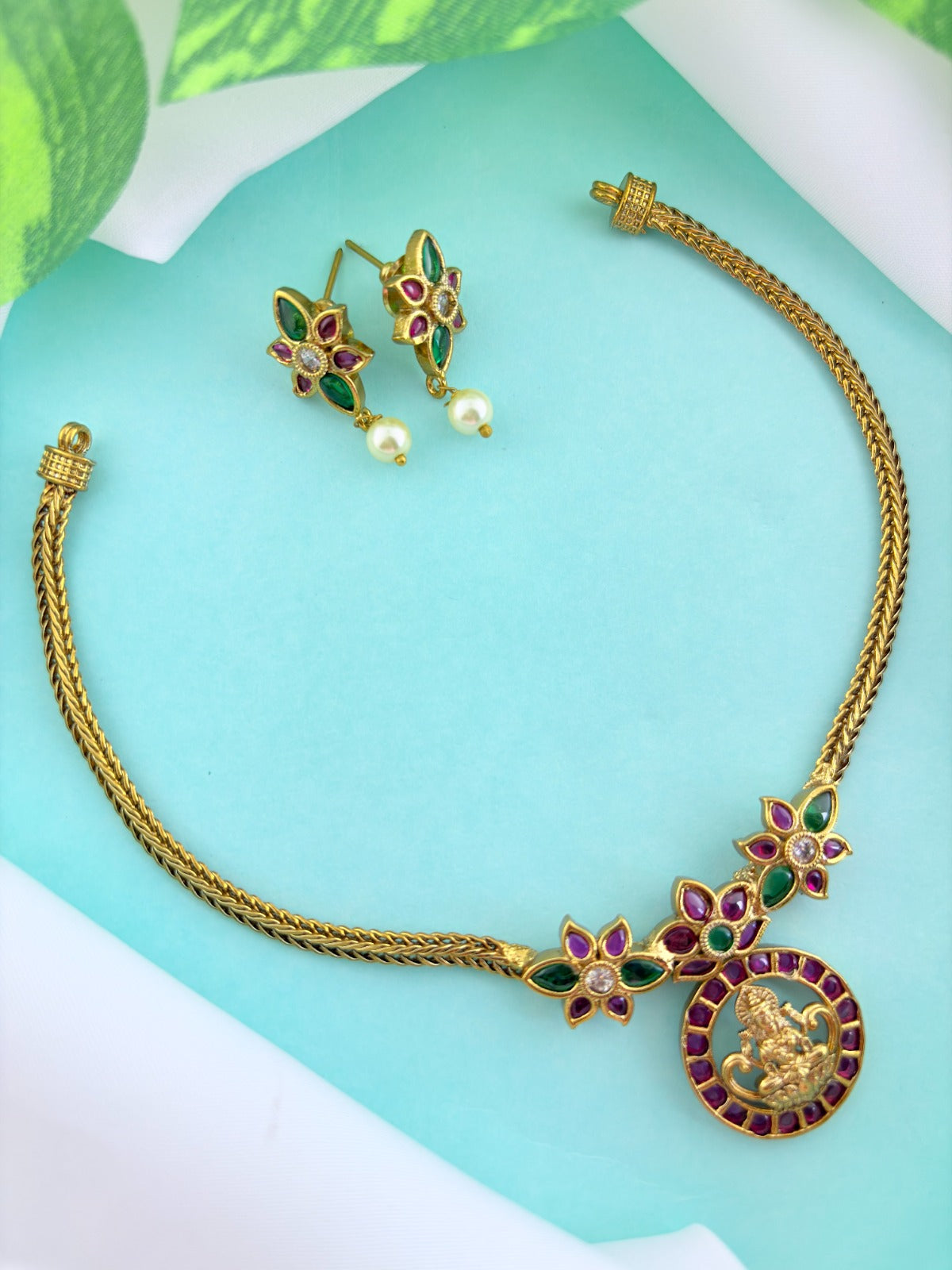 Premium antique finish necklace showcasing classic rich ruby and green stones with a Lakshmi pendant and matching earrings