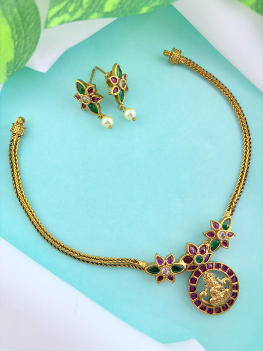 Premium antique finish necklace showcasing classic rich ruby and green stones with a Lakshmi pendant and matching earrings