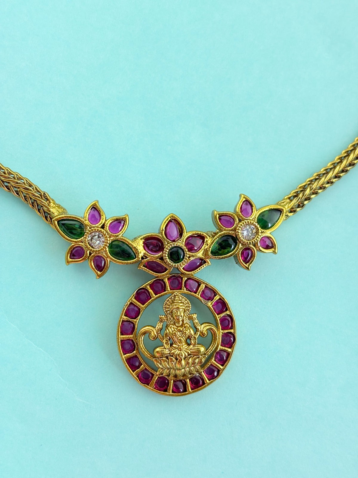Premium antique finish necklace showcasing classic rich ruby and green stones with a Lakshmi pendant and matching earrings