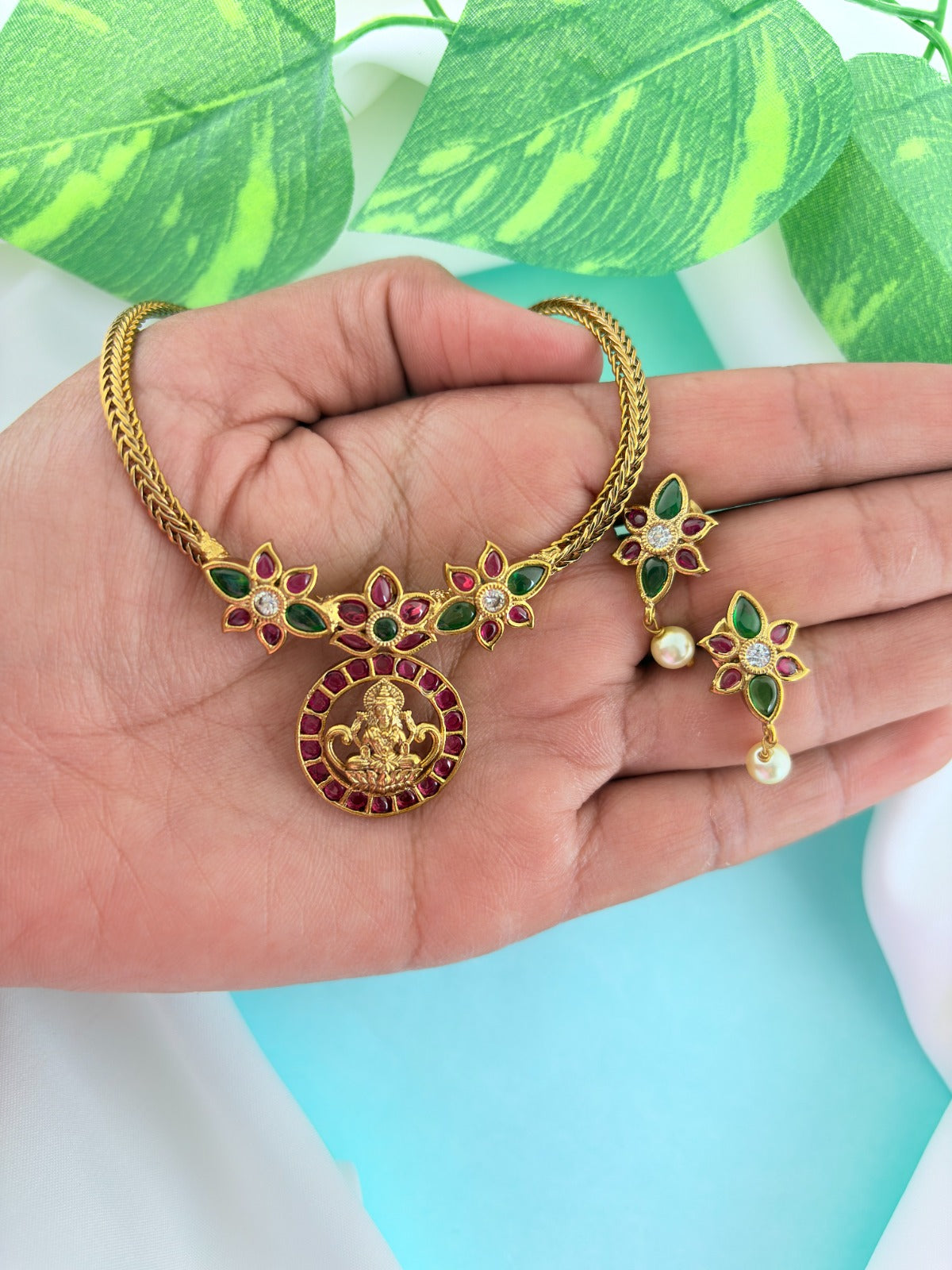 Premium antique finish necklace showcasing classic rich ruby and green stones with a Lakshmi pendant and matching earrings