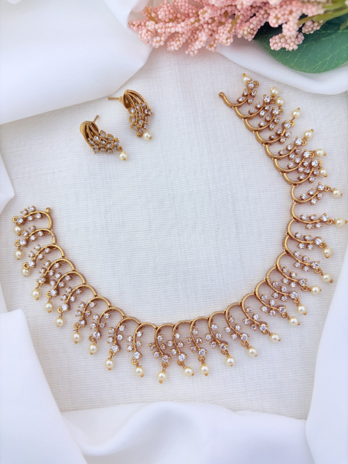Premium matte finish necklace and earrings adorned with stones and pearl drops for a graceful appeal