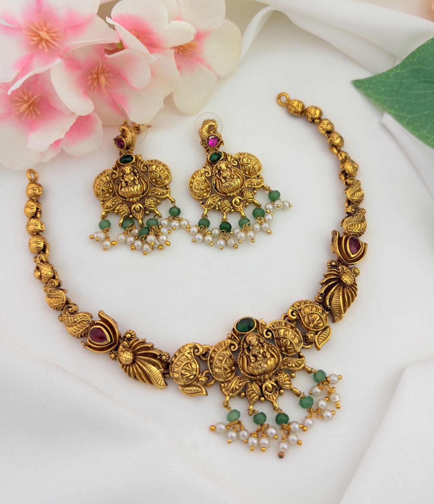 Traditional temple jewellery featuring intricate divine motifs, rich antique detailing, ruby and green stones