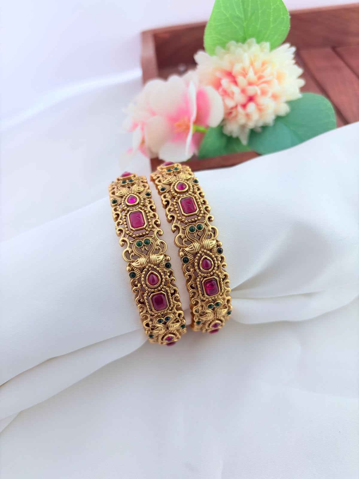 Elegant matte finish bangles embellished with vibrant ruby and green stones for a timeless traditional look