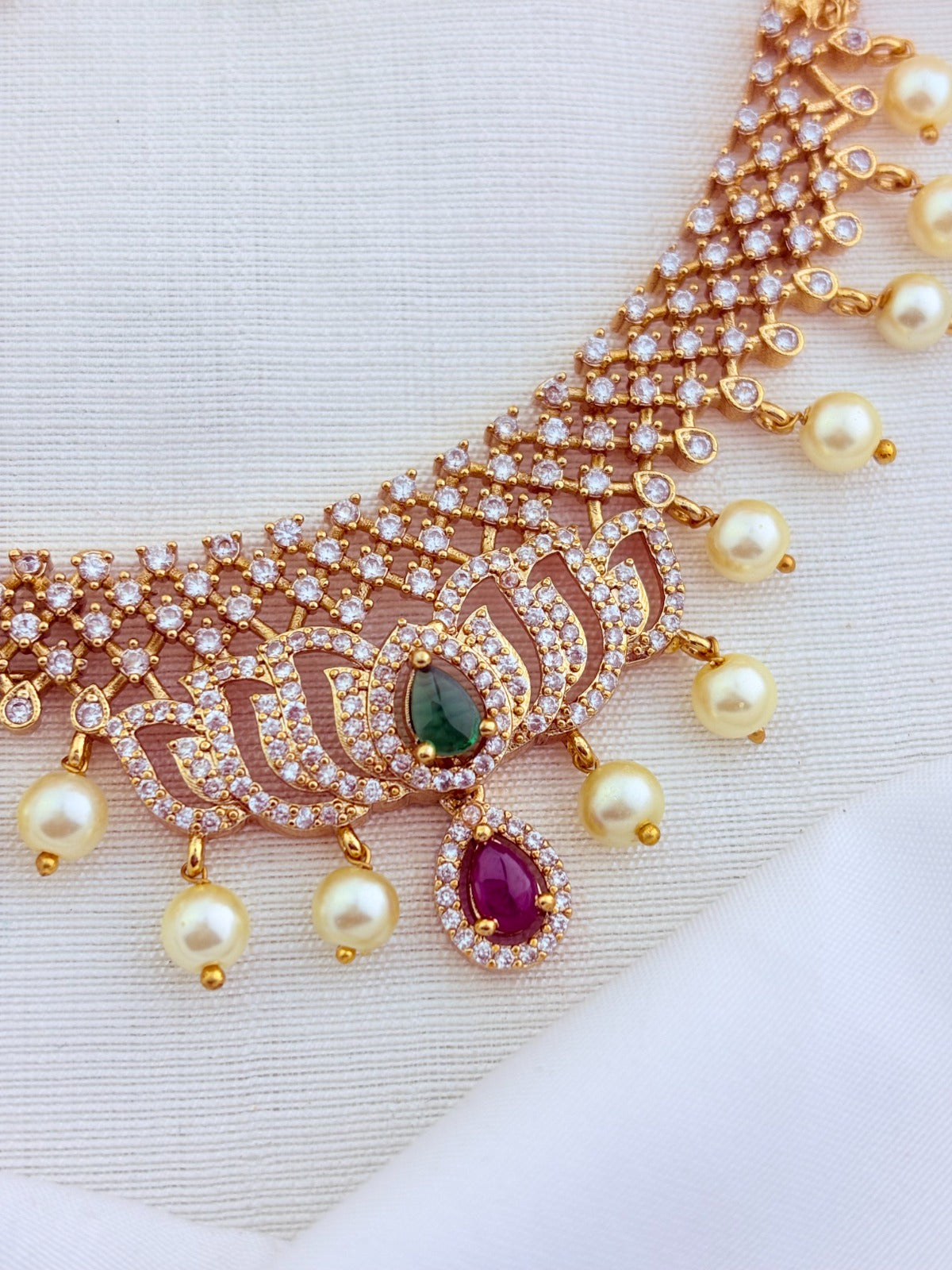 Classic lotus motif necklace adorned with AD stones and elegant pearl drops with matching earrings