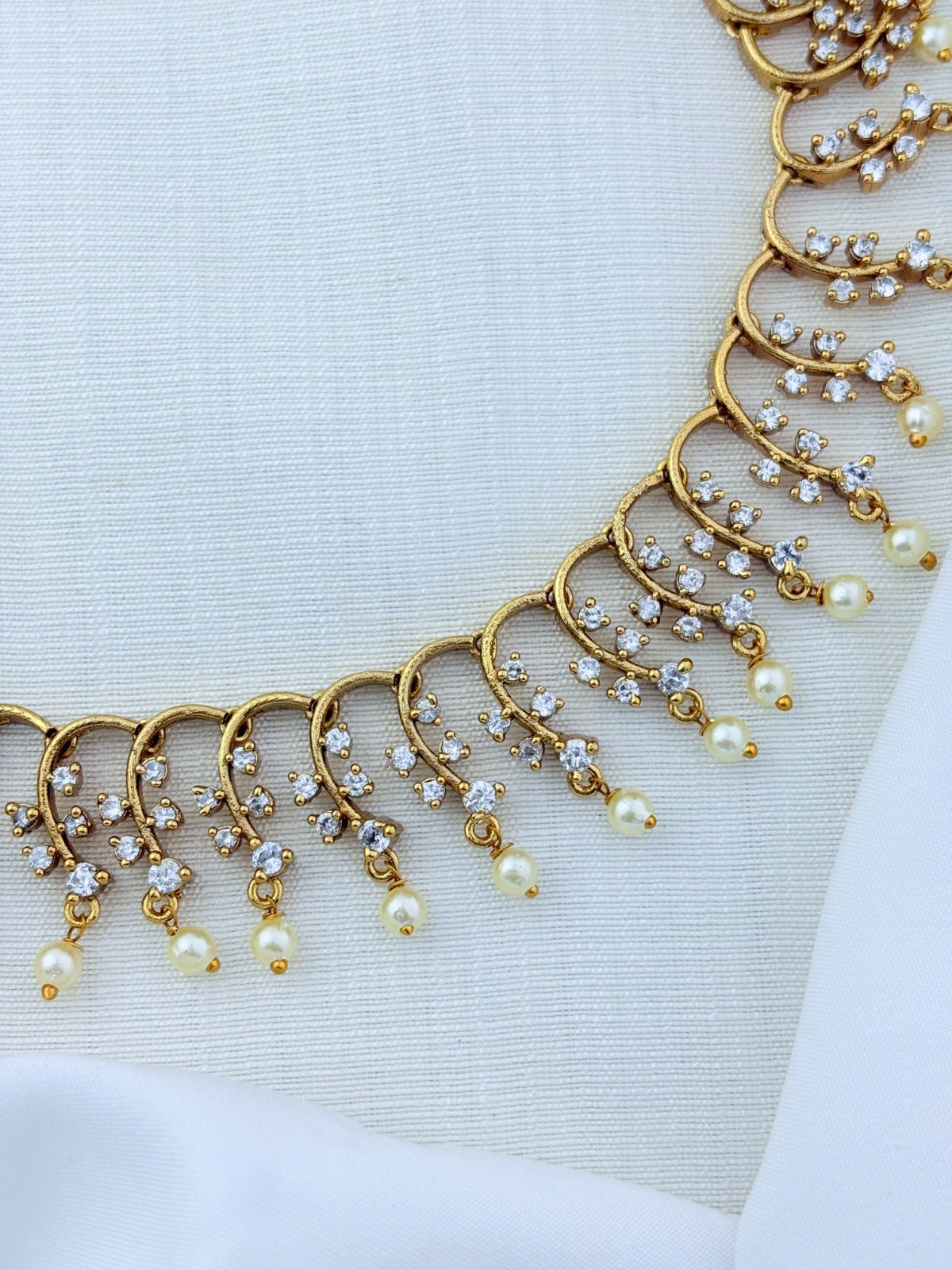 Premium matte finish necklace and earrings adorned with stones and pearl drops for a graceful appeal